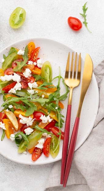 Ensalada de tomate vista superior con queso feta y cubiertos