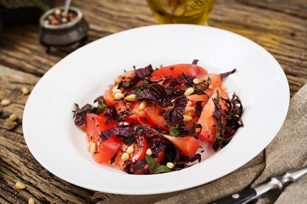 Ensalada de tomates con albahaca violeta y piñones. Comida vegana. Comida italiana