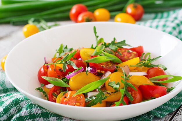 Ensalada de tomates cherry frescos con cebolla y rúcula