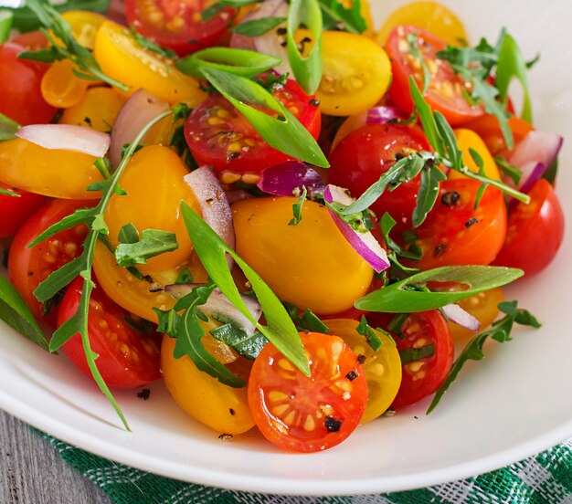 Ensalada de tomates cherry frescos con cebolla y rúcula