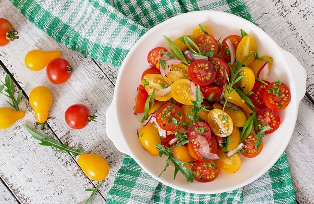 Ensalada de tomates cherry frescos con cebolla y rúcula