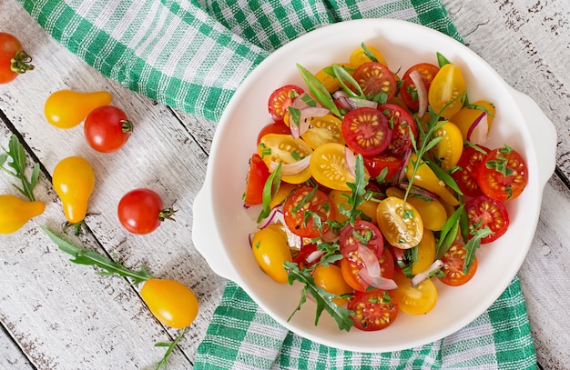 Ensalada de tomates cherry frescos con cebolla y rúcula