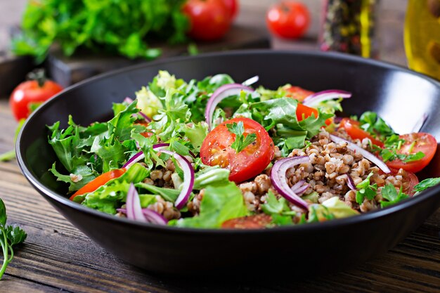 Ensalada de trigo sarraceno con tomates cherry, cebolla roja y hierbas frescas. Comida vegana. Menú de dieta