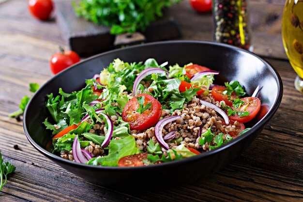 Ensalada de trigo sarraceno con tomates cherry, cebolla roja y hierbas frescas. Comida vegana. Menú de dieta