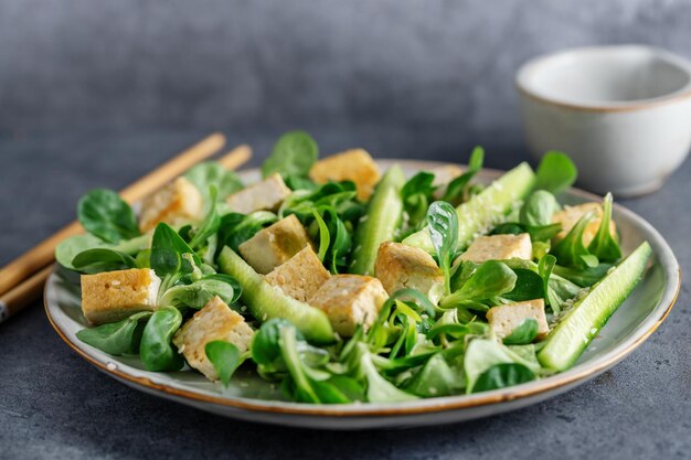 Ensalada vegana con pepino tofu y sésamo servido en plato Primer plano