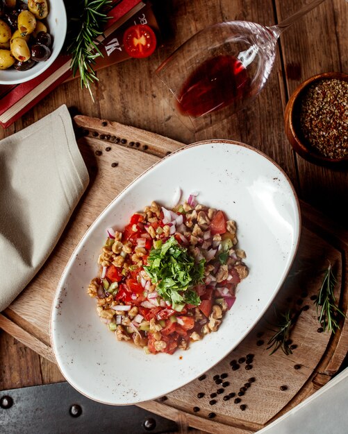 Ensalada de vegetales frescos con cubitos de tomate, nuez, cebolla roja y hierbas