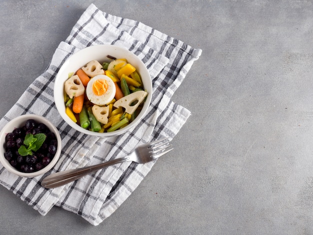 Ensalada vegetariana con bayas en mesa gris