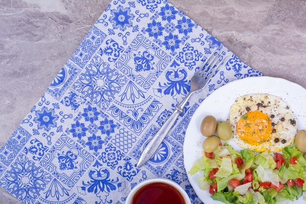 Ensalada verde con huevo frito y una taza de té