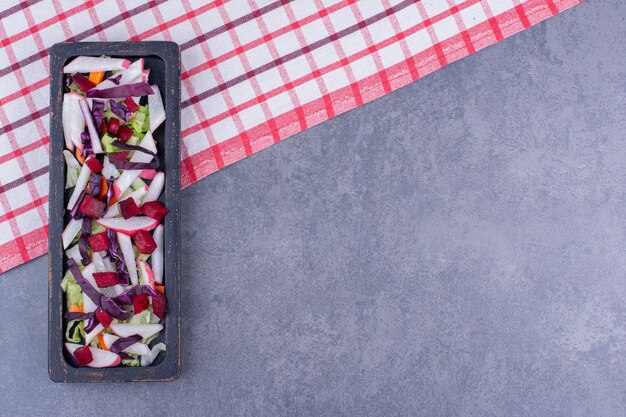 Ensalada verde con ingredientes en bandeja negra.