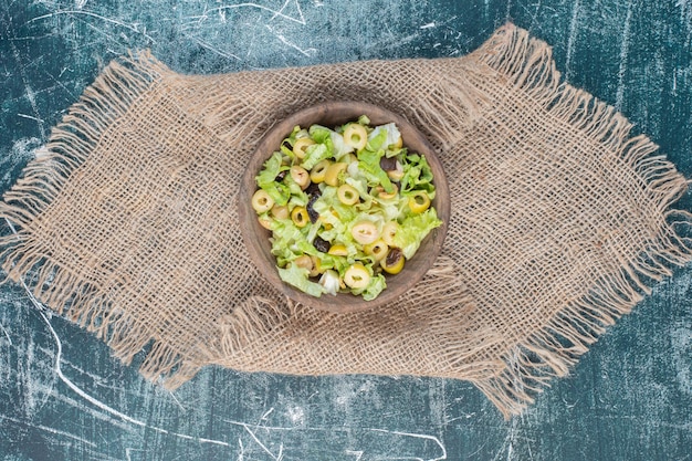 Foto gratuita ensalada verde con lechuga picada sobre superficie azul.