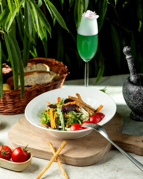 Ensalada verde con lechuga, tomate cherry, pepino, col y palitos de pan