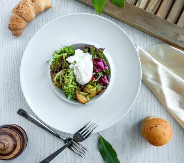 Ensalada verde con papas en el plato blanco