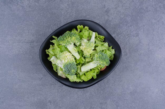 Ensalada verde en un plato sobre superficie azul