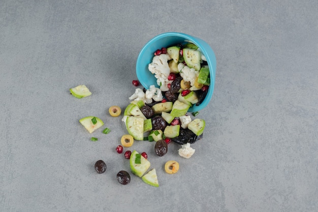 Ensalada verde en una taza azul con aceitunas negras y manzanas