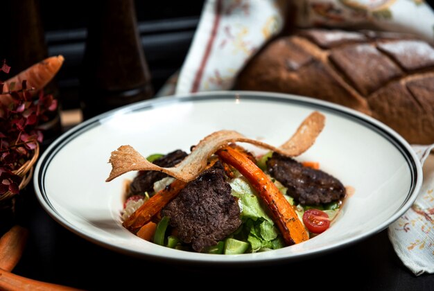 Ensalada de verduras con carne a la parrilla y zanahorias fritas