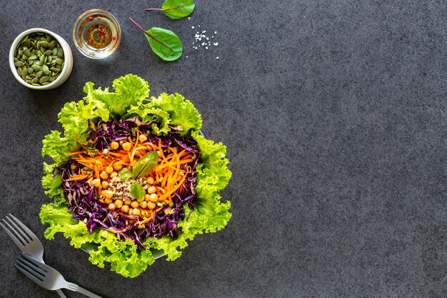 Ensalada de verduras frescas en un plato en negro. Vista superior