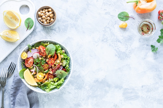 Ensalada de verduras frescas en un plato sobre la superficie de hormigón blanco