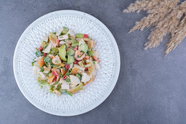 Ensalada de verduras y hierbas picadas sobre superficie azul