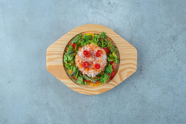 Ensalada de verduras con hierbas en un plato de madera.