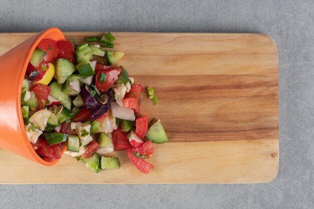Ensalada de verduras con ingredientes mixtos sobre una tabla de madera.