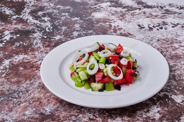 Ensalada de verduras con ingredientes picados y picados mezclados con aceite