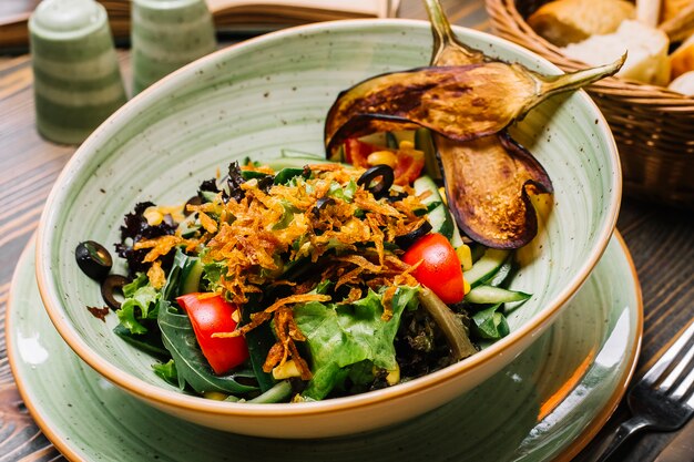 Ensalada de verduras lechuga tomate pepino aceitunas callos berenjenas fritas vista lateral