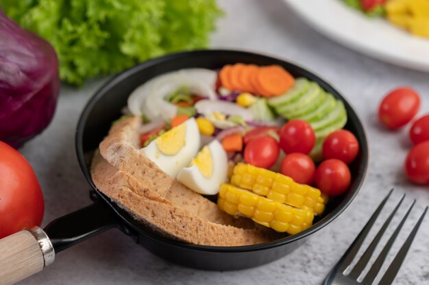 Ensalada de verduras con pan y huevos en la sartén.