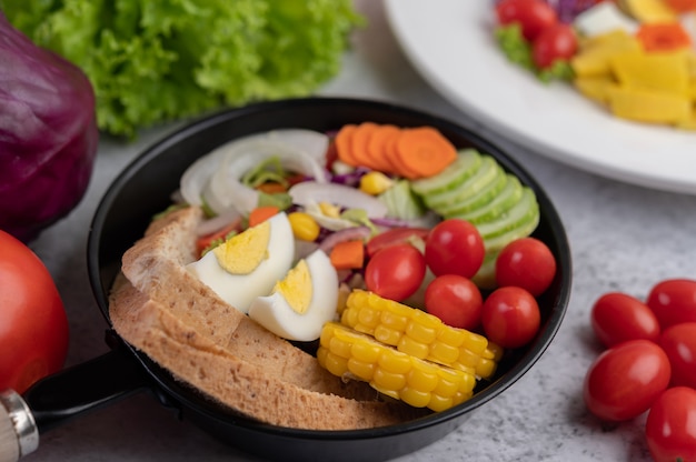 Ensalada de verduras con pan y huevos en la sartén.