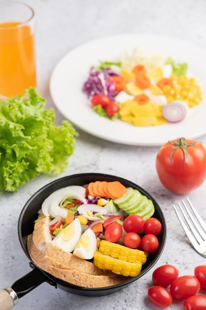 Ensalada de verduras con pan y huevos en la sartén.