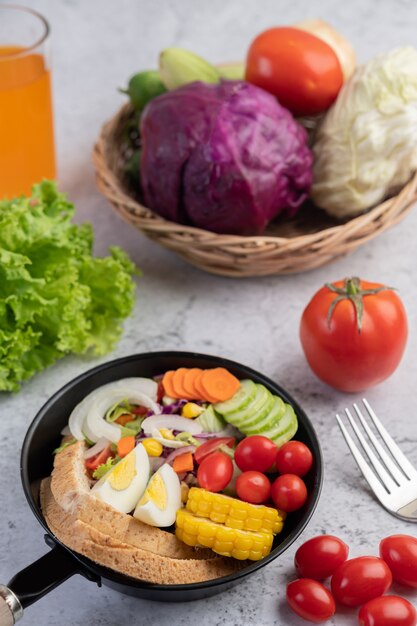 Ensalada de verduras con pan y huevos en la sartén.