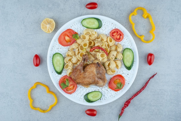 Ensalada de verduras en un plato blanco con deliciosos macarrones sobre fondo de mármol