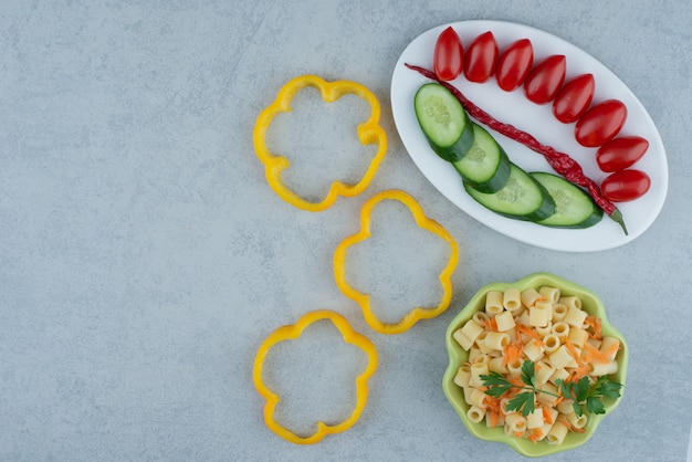 Ensalada de verduras en un plato blanco con macarrones sobre fondo de mármol. Foto de alta calidad