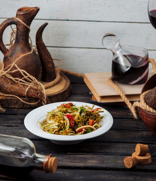 Ensalada de verduras en plato blanco con vino.