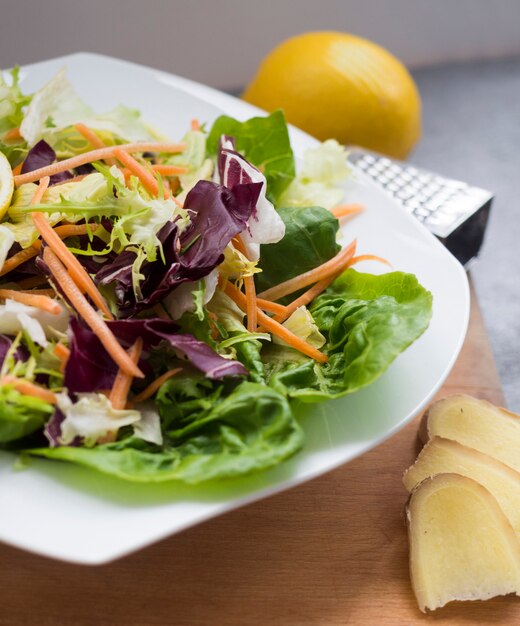 Ensalada de verduras en un plato con limón en la mesa