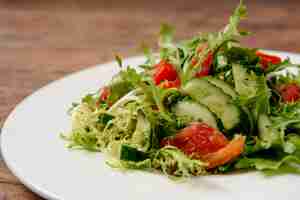 Foto gratuita ensalada de verduras en plato redondo blanco sobre mesa de madera.