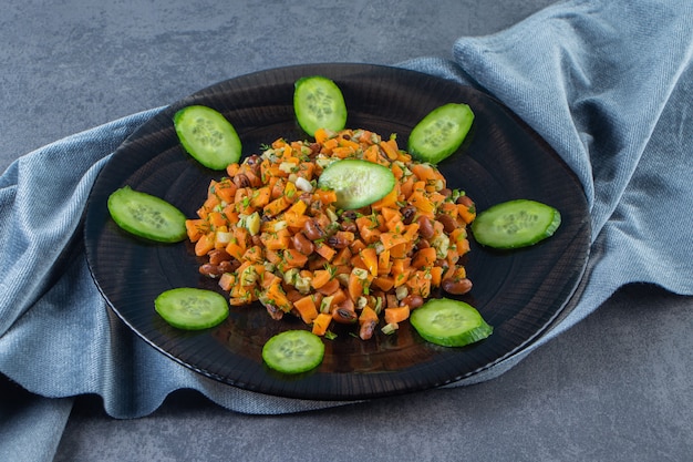 Ensalada de verduras en un plato sobre una toalla sobre la superficie de mármol