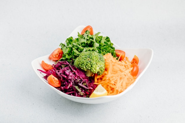 Ensalada de verduras con repollo picado, zanahoria, rodajas de tomate, lechuga y brócoli.