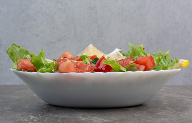 Ensalada de verduras con rodajas de limón en un plato blanco. Foto de alta calidad