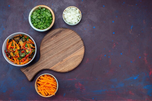 Ensalada de verduras en rodajas de vista superior dentro de la placa con verduras en el escritorio oscuro