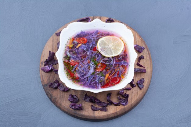 Ensalada de verduras y salsa con repollo morado en un cuenco de cerámica blanca.