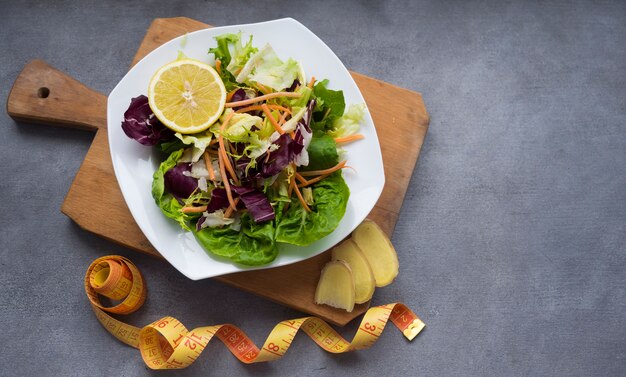 Ensalada de verduras en tablero de madera con cinta métrica en la mesa