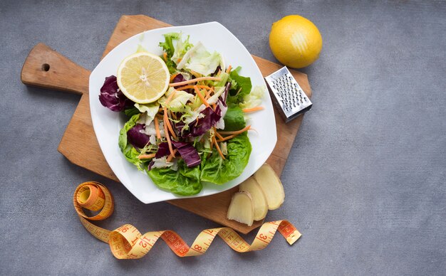 Ensalada de verduras en tablero de madera con cinta métrica