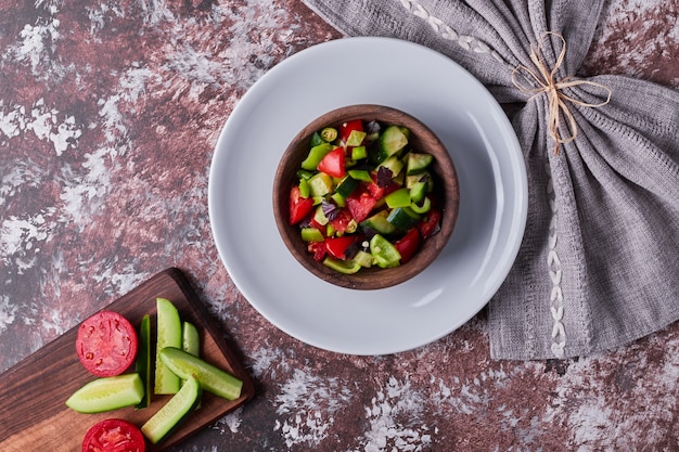 Ensalada de verduras en una taza de madera en un plato blanco.