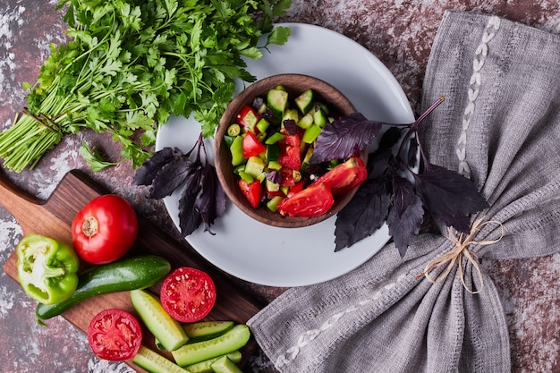 Ensalada de verduras en una taza de madera servida con hierbas, vista superior