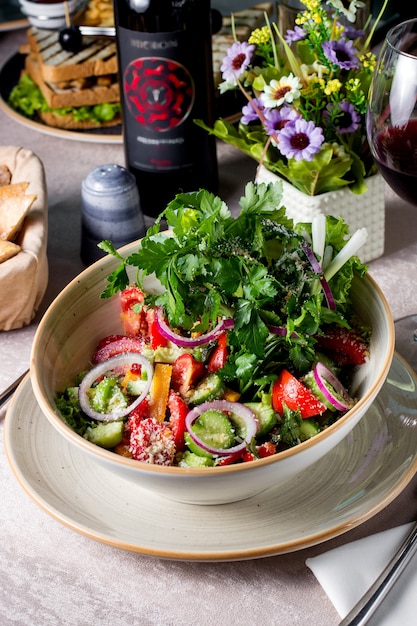 Ensalada de verduras con tomate, pepino, pimiento, cebolla roja, parmesano rallado y perejil