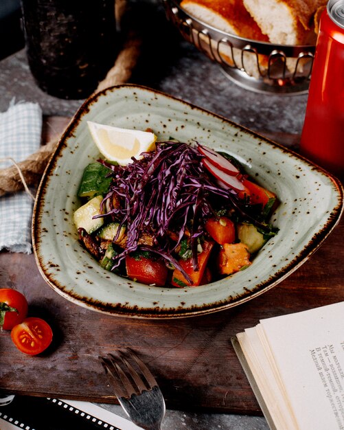 Ensalada de verduras con tomates, pepinos, rábanos, repollo y rodaja de limón.