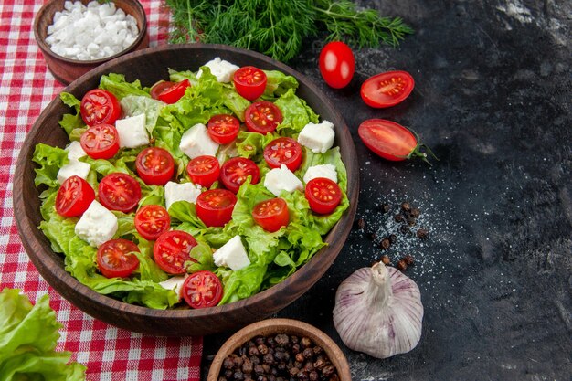 Ensalada de verduras de vista frontal con tomates con queso en rodajas y condimentos sobre fondo oscuro comida comida dieta almuerzo color