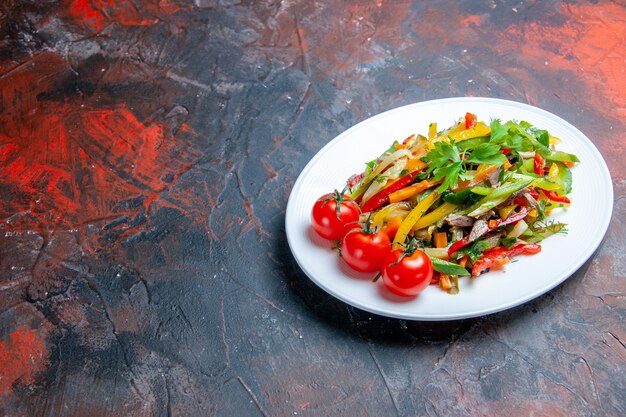 Ensalada de verduras de vista inferior en placa ovalada sobre superficie de color rojo oscuro con lugar de copia