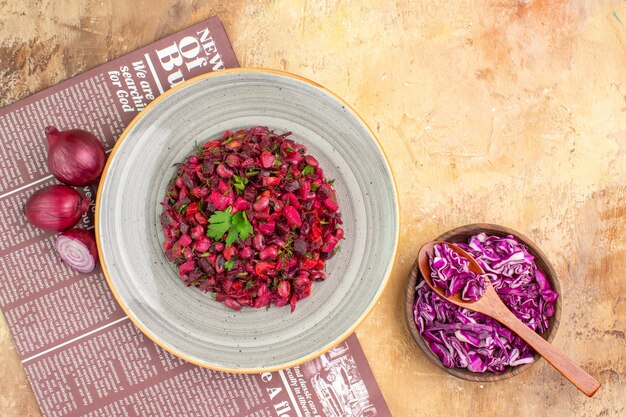 Ensalada de verduras vista superior en una gran placa gris hecha de cebollas rojas, perejil y col roja picada en una mesa de madera con lugar para copiar