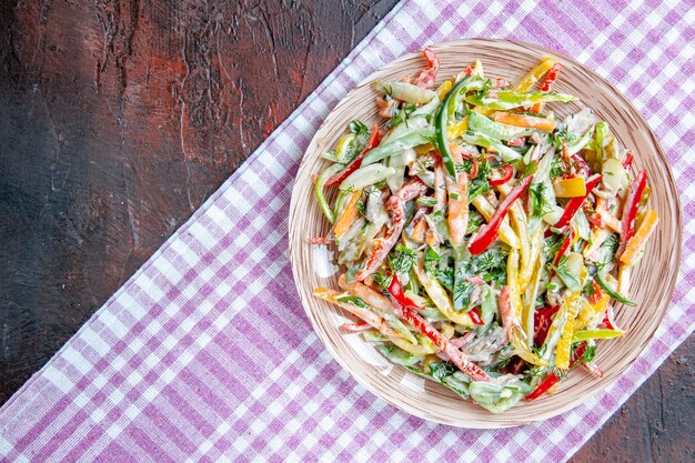 Ensalada de verduras vista superior en plato sobre mantel en lugar libre de mesa rojo oscuro